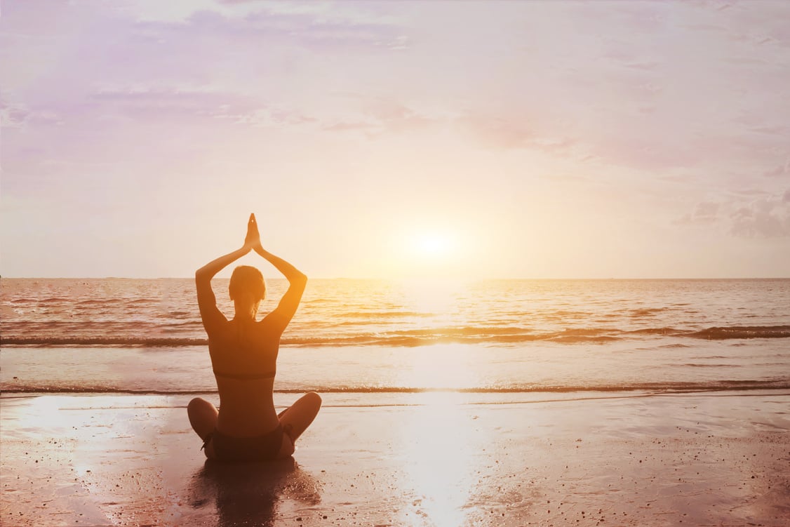 Yoga and meditation background silhouette of beautiful woman practicing breath exercises on the sea beach. Body mind and spirit, mindfulness concept. Enlightenment and healthy lifestyle